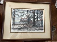 Framed painting of a farm house in a wooded setting with adjacent shed and bare trees. The frame is included and the artwork is matted.