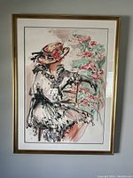 Framed lithograph showing a woman in a red hat seated with flowers, full view of artwork and frame
