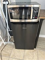 Photo showing a Toshiba microwave placed on top of a Hisense mini fridge, both appliances visible in their entirety.