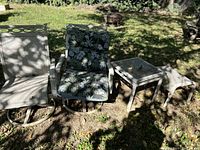 Outdoor furniture set on grass including two chairs and two side tables in shaded yard