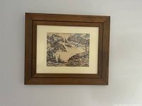 Photo of the framed snowy mountain print hanging on a plain wall, showing the entire frame and artwork clearly.