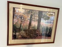 Image shows a framed photograph of a wooden wagon in the woods during autumn with colorful fall leaves and a wooden wagon with large spoked wheels. The frame is bamboo-style brown wood with double mats in cream and burgundy colors.