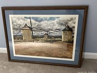 Framed print showing several traditional windmills under a dramatic cloudy sky, with matting and a wood-textured frame. The print measures approximately 3x2 feet.