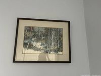 Photo of framed artwork showing a winter trees forest scene with snow on the ground.