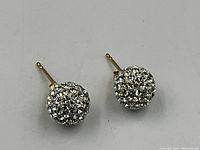 Pair of round stud earrings with clear crystals in spherical cluster design on white background.