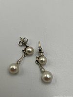 Pair of earrings shown front view, both top and drop pearls visible