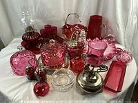 Overhead view of entire collection showing cranberry glass pieces with hobnail textures, clear crystal bowl and silver-plated accents