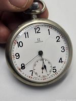 Front view showing white enamel dial, Arabic numerals, blued hands and subsidiary seconds