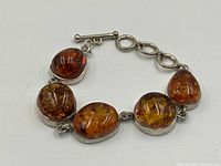 Bracelet laid flat showing five amber cabochon stones set in sterling silver and toggle clasp