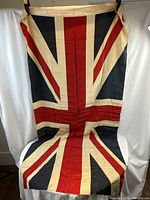 Full view of vintage British flag showing Union Jack design hung vertically.