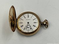 Watch opened to show white enamel dial with Roman numerals and subsidiary seconds