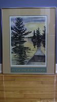 Full view of the framed Algonquin Park poster by Ric Liesch showing the poster with beige matting inside a slim light-colored frame.