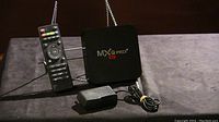 MXQ Pro+ TV box with remote and power adapter showing front and sides