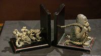 Full view of both bookends showing the gorilla on one side holding the rope and the group of monkeys pulling on the other side, mounted on black wooden bases with red trim.