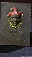 Front view of cast iron door greeter plaque showing jester face and greeting text