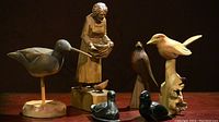 All six bird figurines and wooden old lady sculpture arranged together for full lot overview.