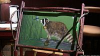 Front view of the serving tray showing the raccoon beside water framed by natural twig and branch handles