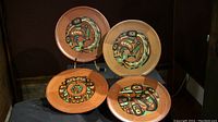 Photo front view of four cedar plaques with colorful painted Native designs