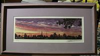 Full view of framed print depicting a sunset scene with trees and a church steeple under a colorful sky
