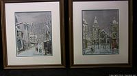 Two framed winter village scene prints side by side showing street and church scenes in Montmartre.
