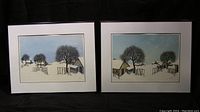 Two framed winter farm prints side by side featuring snowy rural landscapes with barns, fences, trees and a church steeple under a blue sky. Both signed Pinson.