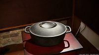 Photo of the closed dutch oven on a small table showing its oval shape and lid with cast iron handle.