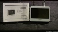Front view of Lennox ComfortSense 7500 thermostat with user guide, showing color touchscreen