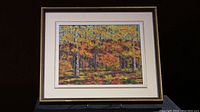 Framed oil painting showing entire artwork of autumn forest with fall foliage.