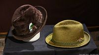 Two beaver felt hats displayed on black surface, dark brown on left and lighter brown on right.