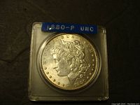 Obverse of 1880-P Morgan Silver Dollar coin in plastic holder with blue label indicating uncirculated condition.