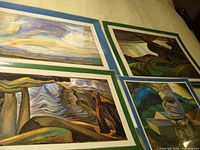 Four laminated Emily Carr prints laid out on a surface showing various nature-inspired scenes including clouds, trees, and a totem pole