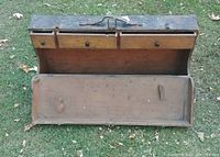 Open top view showing three small wooden drawers on top and a large hinged compartment below with leather straps inside.