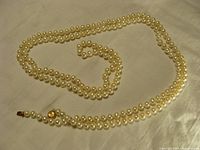 Full view of the long pearl necklace laid out to show length and uniform pearls.
