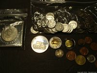 Coins spread showing a coin in protective bag, various circulated coins including commemorative coins and pennies.