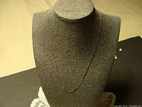 Full view of the gold chain necklace displayed on bust stand, showing length and drape.