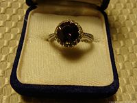 Front view of amethyst sterling silver ring on cream colored box interior with blue border.