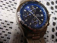 Close-up photo of the watch face showing blue dial, subdials, date window and tachymeter bezel.