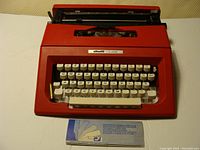 Front view of red Olivetti College typewriter with instruction booklet visible below