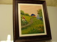 Frontal photo of the closed key box showing the painted countryside landscape with houses, trees, and grassy hills.