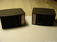 Front left and right view of two black Bose Model 141 speakers with fabric and solid panel front grille.