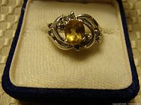 Front view of sterling silver ring with oval yellow citrine gemstone in decorative setting inside box.