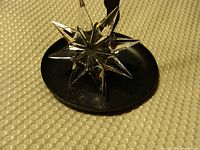 Crystal star Christmas ornament displayed on black stand showing multi-faceted points and clarity of crystal.