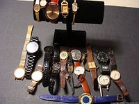 Overview of all fourteen assorted wristwatches showing a variety of face shapes, dial colors and band materials