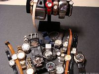 Full lot showing 18 wristwatches in various styles and bands arranged on a display.