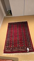Full image of red area rug measuring approximately 6 feet by 4 feet on floor.