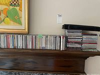 Shelf displaying about 70 CDs mainly classical and jazz in jewel cases, arranged side-by-side and stacked