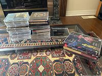 Photo of stacked CDs showing about 40 classical music CDs in jewel cases and slim cases, arranged on a table and floor covering.