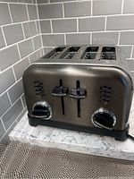 Front view of the Cuisinart four slice toaster showing control levers, dials, and LED indicators on a kitchen countertop.