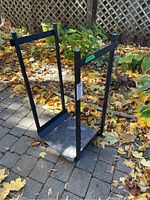 Side view of the black cast iron firewood storage rack showing the vertical supports and rectangular base.