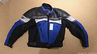 Front view of the motorcycle jacket showing color blocking in black, blue, white. Leather and textile materials and zippered front closure.